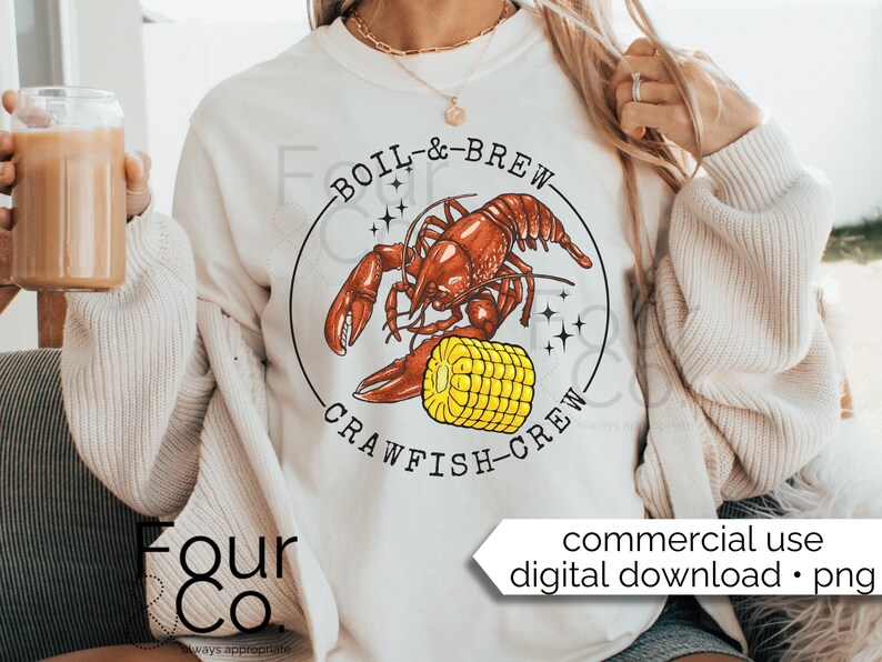 May include: A white sweatshirt with a graphic design of a red crawfish holding a yellow ear of corn. The text "BOIL & BREW CRAWFISH CREW" is printed in a black circle around the crawfish.