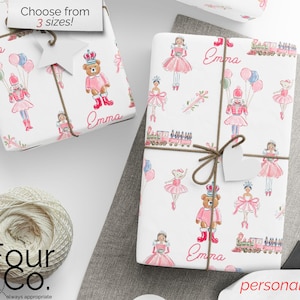May include: White wrapping paper with a repeating pattern of pink ballerinas, toy soldiers, teddy bears, and trains. The name "Emma" is printed on the paper. The wrapping paper is tied with twine and a blank tag.