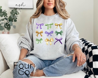 Puede incluir: Una sudadera gris con un diseño de nueve lazos coloridos en varios tonos de verde, morado y amarillo. Los lazos están dispuestos en una cuadrícula en la parte delantera de la sudadera.