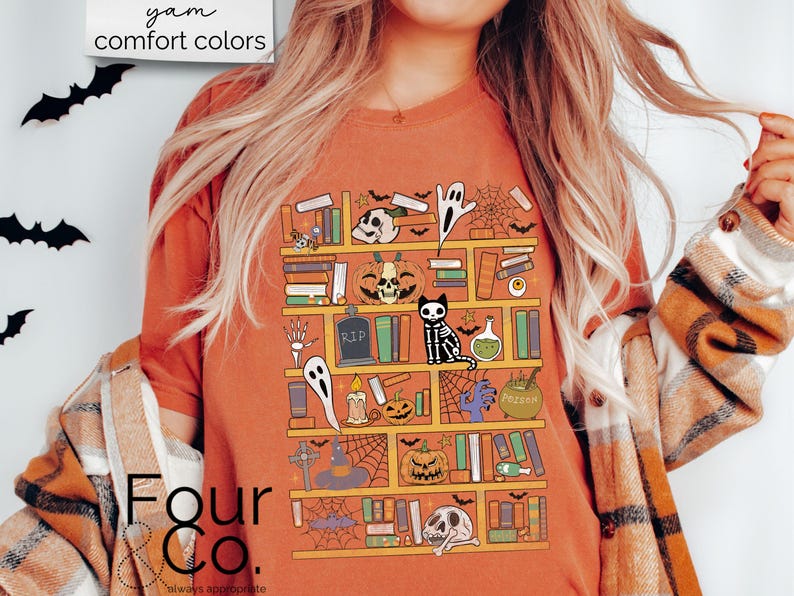 May include: A burnt orange t-shirt with a graphic of a bookshelf filled with spooky Halloween themed items, including books, pumpkins, ghosts, a skeleton cat, and a potion bottle. The text "Four & Co." is visible in the bottom left corner of the image.