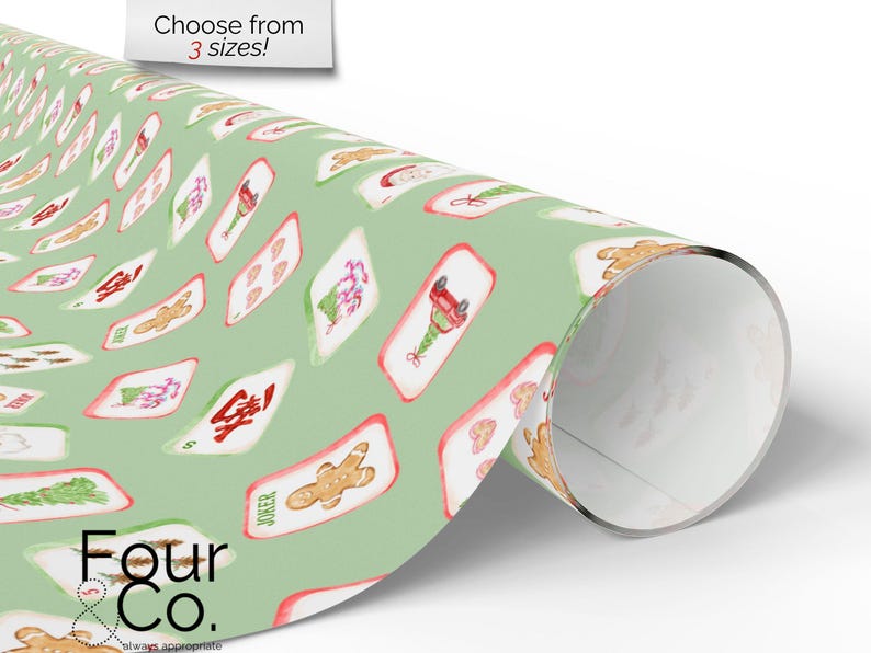 May include: A roll of wrapping paper with a light green background and a repeating pattern of Christmas-themed playing cards. The cards feature gingerbread men, Christmas trees, and other festive designs. The text "Choose from 3 sizes!" is visible.