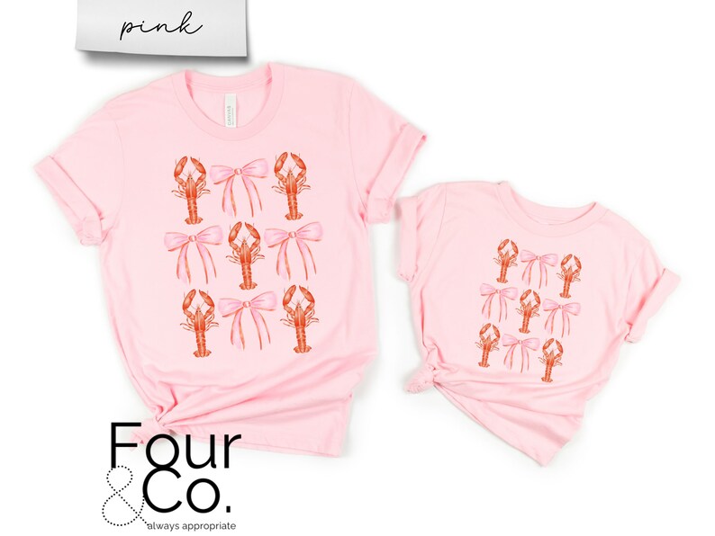 May include: Two pink t-shirts with a pattern of pink bows and orange lobsters. The larger shirt has the text "Four & Co. always appropriate" printed on the bottom.