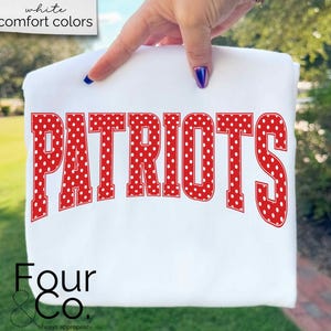 May include: White t-shirt with the word "PATRIOTS" in large red letters with white polka dots. The shirt also has the text "Four & Co." and "white comfort colors" printed on it.