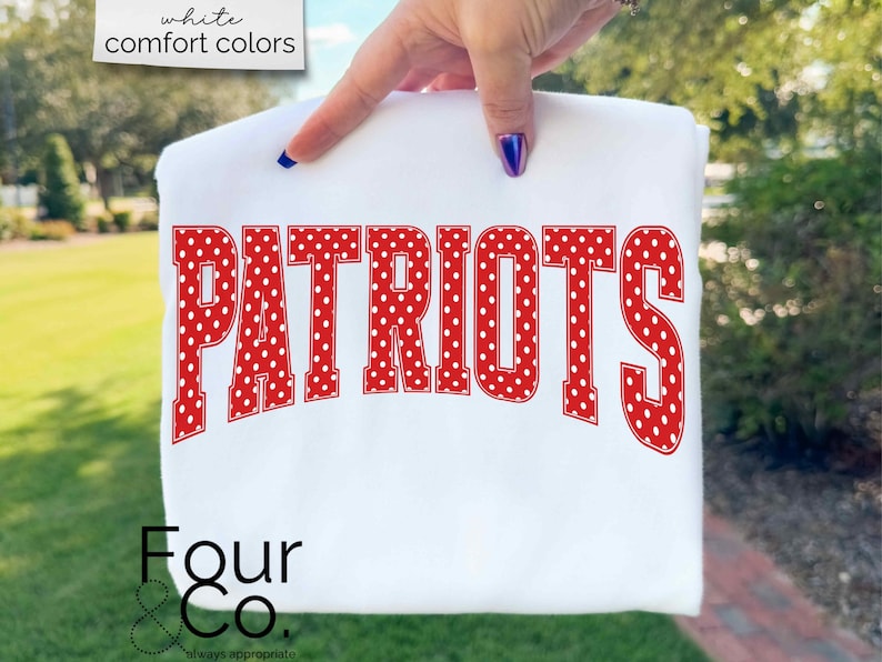 May include: White t-shirt with the word "PATRIOTS" in large red letters with white polka dots. The shirt also has the text "Four & Co." and "white comfort colors" printed on it.