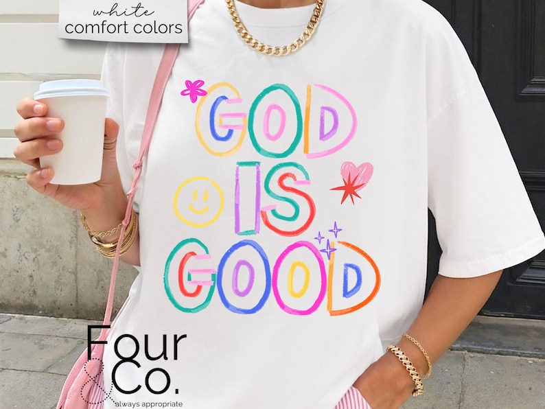以下が含まれることがあります： カラフルで遊び心のある文字で「GOD IS GOOD」と書かれた白いTシャツ。デザインにはスマイリーフェイス、ハート、星が含まれています。シャツは半袖で、ゆったりとしたフィット感です。