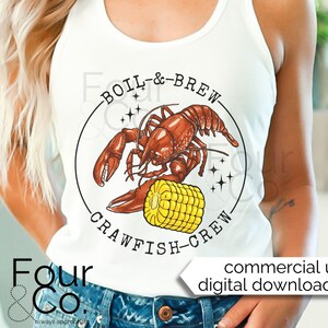 May include: White tank top with a graphic of a crawfish holding a corn cob. The graphic is surrounded by a circle with the text "Boil & Brew Crawfish Crew".