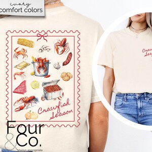 May include: A beige t-shirt with a red and white graphic of a crawfish boil with the text "Crawfish Season" and the logo "Four & Co. always appropriate".