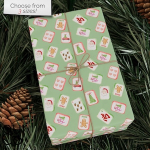 May include: A wrapped gift with a light green background, adorned with a repeating pattern of Christmas-themed playing cards. The cards feature images of Santa, gingerbread men, Christmas trees, and other holiday symbols. The gift is tied with twine and the text "Choose from 3 sizes!" is in the top left corner.