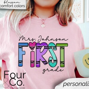 May include: Pink t-shirt with the text "Mrs. Johnson First Grade" in rainbow colors. The text is made to look like crayons. The shirt also has the text "Four & Co. always appropriate" at the bottom.