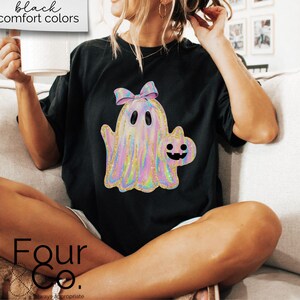 May include: Black t-shirt with a holographic ghost and a pumpkin graphic. The text "Four Co." is on the bottom of the shirt.