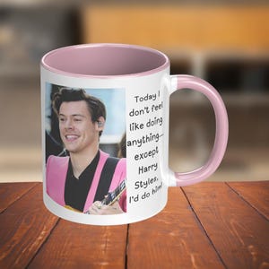 Puede incluir: Una taza de cerámica rosa y blanca con una foto de un hombre sosteniendo una guitarra. La taza tiene un texto que dice "Today I don't feel like doing anything... except Harry Styles, I'd do him!"