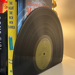 May include: A pair of bookends made from a black vinyl record. The record is a half-circle and has a label that reads "Warner Bros. Records" and "The Monkees" with the album title "Headquarters" and the song title "Daydream Believer".