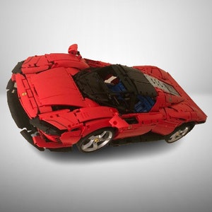 May include: A red Lego model of a Ferrari sports car with black accents and a detailed interior.