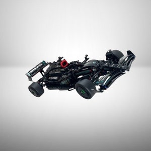 Könnte beinhalten: Ein schwarzes und grünes Lego Formel-1-Rennwagenmodell mit Petronas-Branding. Das Auto hat einen roten Lufteinlass und schwarze Räder.