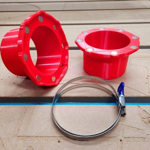 May include: Two red plastic 3D printed parts with a silver metal clamp. The parts have a circular opening and a series of raised circles around the opening.