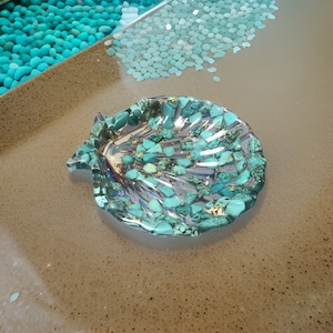 May include: A turquoise seashell-shaped dish with gold flecks and turquoise stones embedded in the resin.