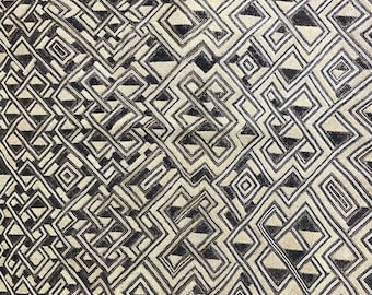May include: A textile with a repeating geometric pattern in shades of brown and beige. The design features interlocking shapes, creating a complex and visually engaging surface. The edges are finished with a darker brown border.