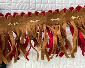 May include: Brown and red fringe trim with embroidered yellow stitching. The fringe is made of felt and has a scalloped edge.