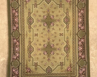 May include: A green and beige rug with a floral pattern. The rug has a geometric design with a central medallion and a border of pink roses.