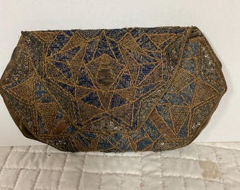 May include: A vintage blue and gold beaded clutch purse with a geometric design. The purse is made of fabric and has a flap closure.