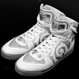 May include: White high-top sneakers with silver accents. The shoes feature a unique design with a textured sole and a lace-up closure. The high-top design includes a padded collar and a decorative emblem.