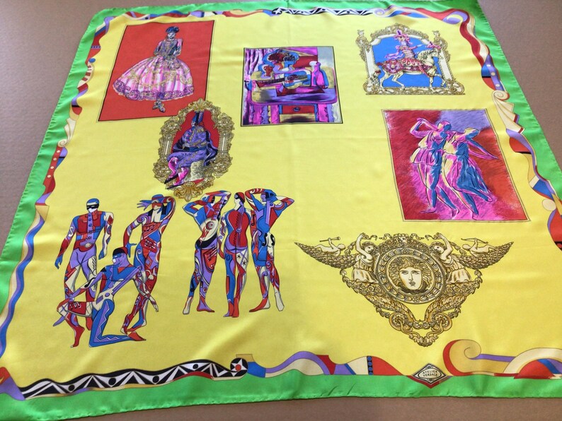 Puede incluir: Un pa&ntilde;uelo de seda amarillo con borde verde e ilustraciones coloridas. El pa&ntilde;uelo presenta im&aacute;genes enmarcadas de figuras en varias poses, incluyendo bailarines y una mujer con un vestido. El dise&ntilde;o incluye un emblema decorativo y patrones geom&eacute;tricos.