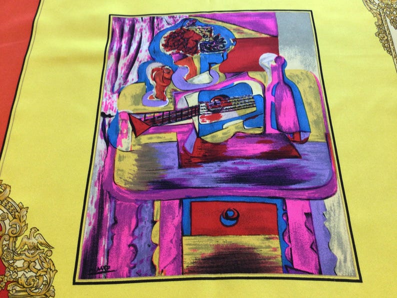 Puede incluir: Un pa&ntilde;uelo de seda colorido con una pintura de estilo cubista de una persona tocando la guitarra, con una botella y elementos de naturaleza muerta. La obra de arte est&aacute; sobre un fondo amarillo con un borde negro y acentos en rojo, rosa y azul.