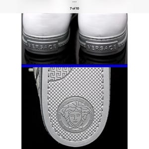 May include: Close-up of white sneakers with silver accents. The heel features the brand name "VERSACE" in silver lettering. The sole has a textured design and a circular emblem with a face.