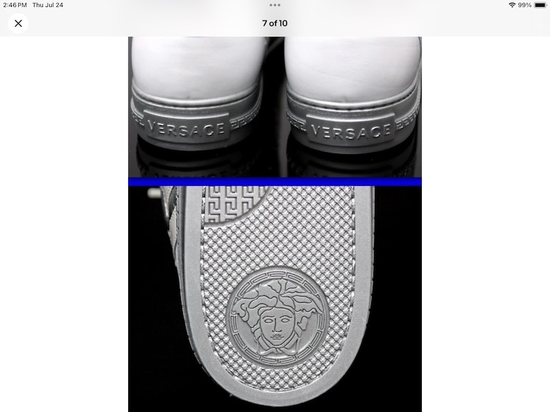 May include: Close-up of white sneakers with silver accents. The heel features the brand name "VERSACE" in silver lettering. The sole has a textured design and a circular emblem with a face.