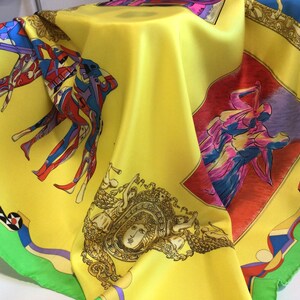 Puede incluir: Un pa&ntilde;uelo de seda amarillo con figuras abstractas coloridas e im&aacute;genes cl&aacute;sicas. El pa&ntilde;uelo presenta un dise&ntilde;o vibrante con figuras rojas, azules y moradas, enmarcadas por un borde verde. El dise&ntilde;o incluye rostros cl&aacute;sicos y detalles ornamentados.