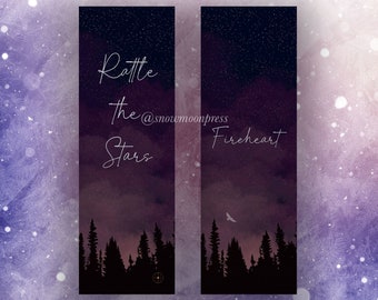 Puede incluir: Dos marcadores de acuarela púrpura y negro con un cielo nocturno estrellado y una silueta de un bosque. El texto en los marcadores dice "Rattle the Stars @snowmoonpress" y "Fireheart".