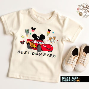 May include: A white short-sleeved t-shirt with a red cartoon race car, Mickey Mouse ears, and the text "BEST DAY EVER".