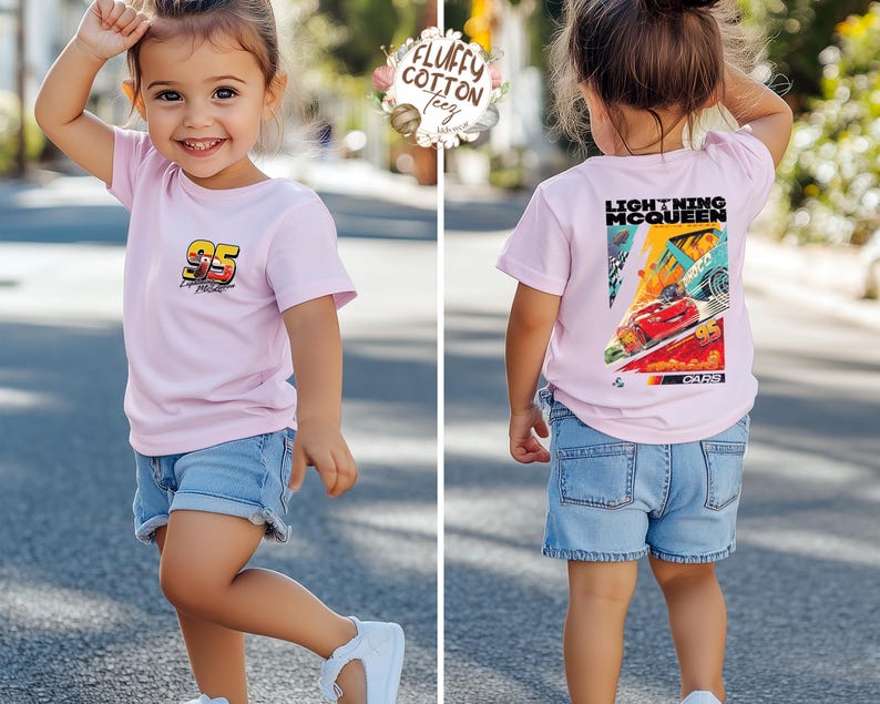 May include: A child in a light pink t-shirt and denim shorts. The t-shirt has the number "95" and "Lightning McQueen" and "Cars" on the back. The child is wearing white trainers. The image is taken outdoors.