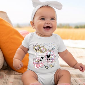Puede incluir: Un beb&eacute; sonriente con un body blanco con gr&aacute;ficos de dibujos animados coloridos de Minnie y Daisy. El texto "Girls just wanna have fun" est&aacute; impreso en el body. El beb&eacute; tambi&eacute;n lleva una diadema blanca.