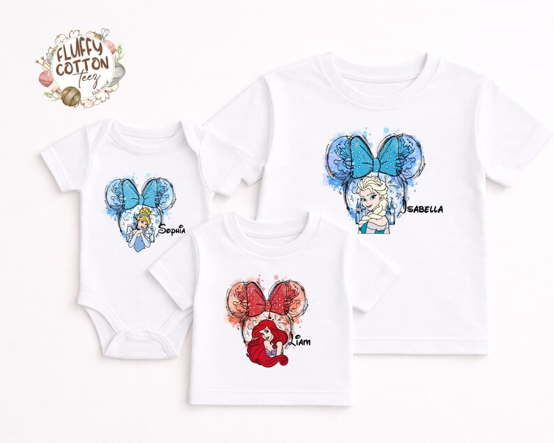 以下が含まれることがあります： ディズニーのプリンセスデザインが施された白いTシャツとボディスーツ。各衣服には、ミッキーマウスの耳の輪郭の中にプリンセスのイラストが描かれています。「Sophia」、「Isabella」、「Liam」という名前がプリントされています。