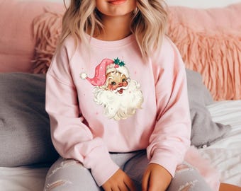 Könnte beinhalten: Ein rosa Sweatshirt mit einer Vintage-Illustration von Santa Claus' Gesicht auf der Vorderseite. Die Illustration ist in Rosa-, Weiß- und Grüntönen gehalten.