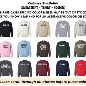 May include: A display of sweatshirts, t-shirts, and hoodies in various colors, including black, white, sand, sport grey, ash, light pink, light blue, dark chocolate, forest, military green, dark heather, charcoal, maroon, navy, and red. Text at the top reads "Colours Available".