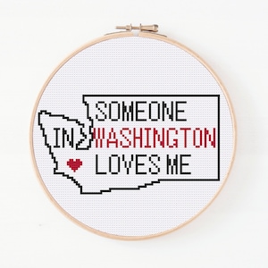 May include: Cross-stitch pattern featuring a red heart and the text "Someone in Washington loves me" inside the outline of the state of Washington.