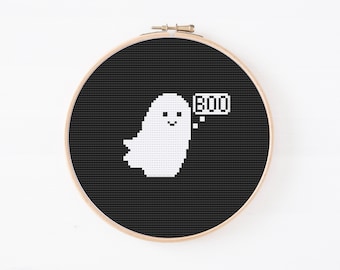 Puede incluir: Un aro de bordado de punto de cruz negro y blanco con un fantasma blanco que dice "BOO" sobre un fondo negro.