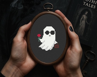 Könnte beinhalten: Eine schwarze und weiße Kreuzstich-Stickerei eines Geistes, der eine Sonnenbrille trägt und eine rote Rose hält. Die Stickerei ist in einem dunklen Holzrahmen gerahmt.