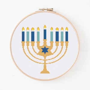 May include: A gold menorah with nine blue and white candles, each with a yellow flame. The menorah has a blue Star of David in the centre.