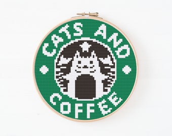 May include: A green and white cross-stitch embroidery hoop with the text "Cats and Coffee" and a stylized image of a cat in the center.