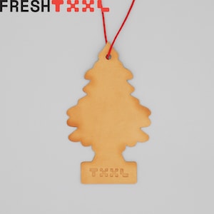 May include: A brown leather car air freshener shaped like a Christmas tree with the word "TXX" printed on the base.