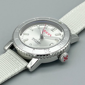 Puede incluir: Un reloj de pulsera plateado con una esfera blanca y detalles rojos. El reloj tiene un bisel negro con marcas blancas y una correa de nailon blanca.