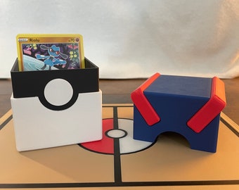 May include: Two Pokemon card deck boxes, one white with a black Pokeball design and the other blue with red accents. The boxes are on a brown playmat with a Pokeball design.
