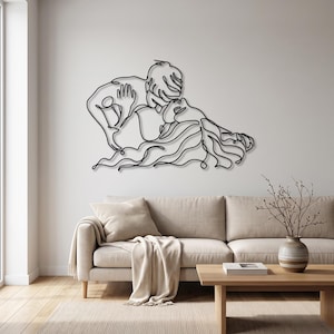 Large metal living room art showing a romantic kissing couple in black minimalist line art, elegantly displayed above a beige contemporary sofa.