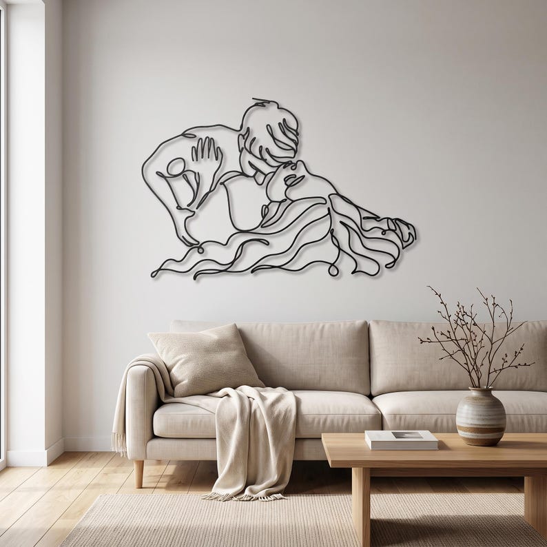 Large metal living room art showing a romantic kissing couple in black minimalist line art, elegantly displayed above a beige contemporary sofa.