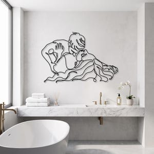 Modern bathroom wall art featuring a romantic continuous line art couple in matte black, positioned elegantly above a sleek white freestanding tub.