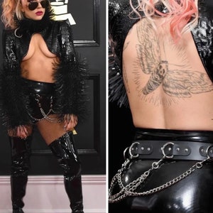 May include: A woman wearing a black leather jacket with fur trim, a black latex skirt, and thigh-high boots. She is wearing a chain belt and has a large moth tattoo on her back.