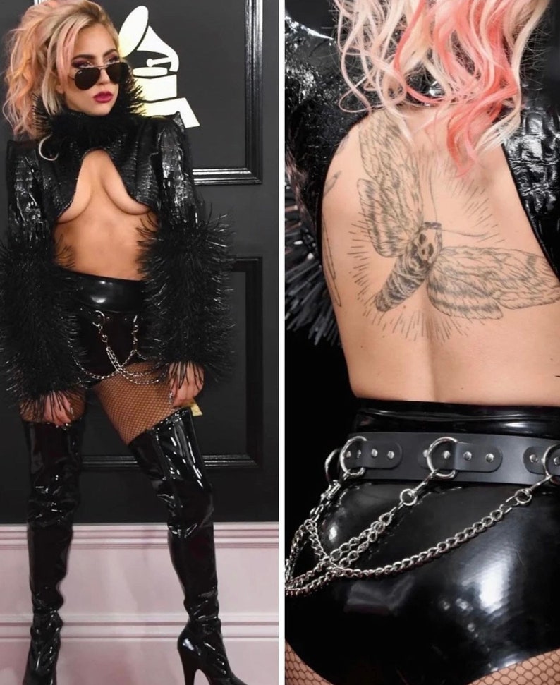 May include: A woman wearing a black leather jacket with fur trim, a black latex skirt, and thigh-high boots. She is wearing a chain belt and has a large moth tattoo on her back.
